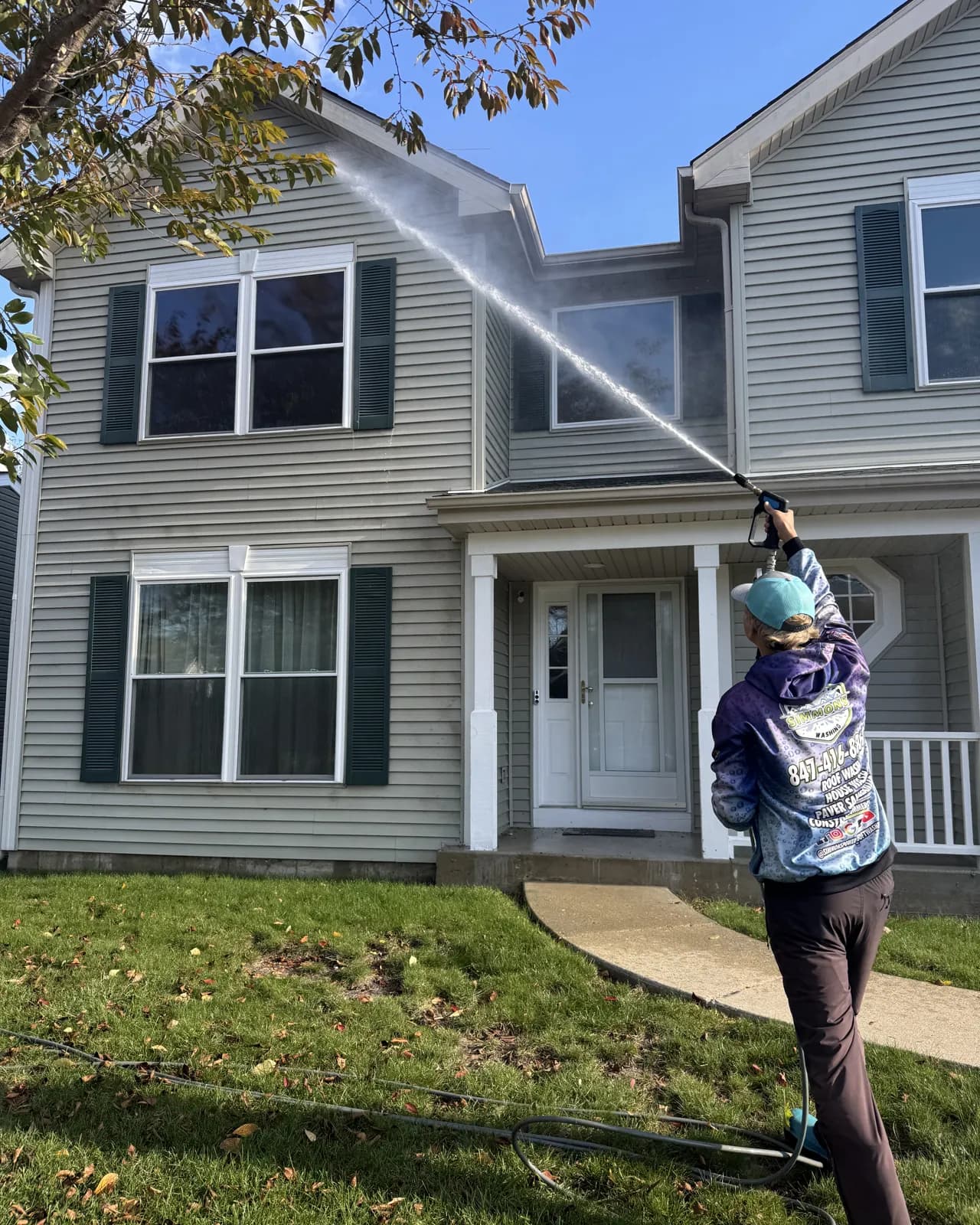 Our crew soft washing a gray two-story vinyl home